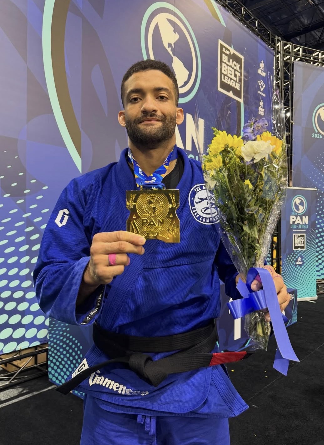 Elementum athlete holding a gold medal and flowers at the IBJJF Pan 2026